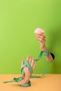 View of woman with measuring tape on hands holding cupcake on green and orange