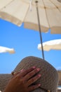 View of a woman`s hands and straw hat on deck chair at a beach. Royalty Free Stock Photo