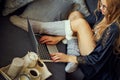 View of a woman`s legs on asofa and a laptop with a coffee mug