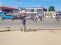 View of a woman selling water on the street, road with cars, people and difficulties as a background. Typically lifestyle in the