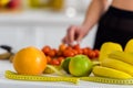 View of woman taking cherry tomato near measuring tape in kitchen