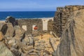 View of woman walking inside Bushiribana ruins toward her red vehicle. Blue water of Atlantic Ocean on background. Royalty Free Stock Photo