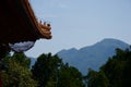 View of wooded Chinese mountains framed by trees and traditional asian roof