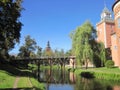 View of a wooden bridge over a moat with water, of the spire of the town hall, a medieval castle with towers