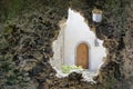 View on a wooden door of a new house through the opening in the wall of an old ruined building Royalty Free Stock Photo