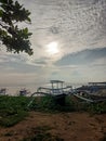 view of a wooden fishing boat on the beach with sunlight and clouds in the background Royalty Free Stock Photo