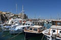 View on wooden fishing boats and white private yachts under blue sky in port of Heraklion near the city center. Royalty Free Stock Photo