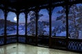 View from wooden gallery of magic winter night in a snowy sea coast surrounded by covered in snow fir trees with full moon in a Royalty Free Stock Photo