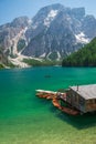 view of wooden house on water with pier and boats lake in dolomites mountains Royalty Free Stock Photo