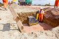 View on wooden ladders placed in trench, worker is compacting foundation using vibration plate compactor