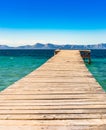 Wooden jetty at blue sea with mountain landscape background Royalty Free Stock Photo