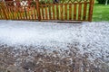 View at wooden terrace with hail stones during hailstorm from sky with sunlight