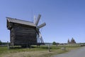 A wooden windmill with a medieval Transfiguration Church on the horizon on Kizhi Island in Karelia