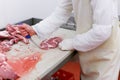 View of a worker in meat factory, chopped a fresh beef meat in pieces on metal work table, industry of processing food. Royalty Free Stock Photo