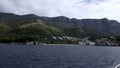 View from the yacht on green tropical hills and cloudy sky. Creative. Waving sea surface and green shore with growing Royalty Free Stock Photo