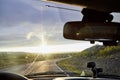 View on yellow sunset and clouds from the car front window and the glare on the glass. Driving car during sunshine in the tundra Royalty Free Stock Photo