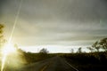 View on yellow sunset and clouds from the car front window and the glare on the glass. Driving car during sunshine in the tundra Royalty Free Stock Photo