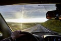 View on yellow sunset and clouds from the car front window and the glare on the glass. Driving car during sunshine in the tundra Royalty Free Stock Photo