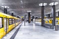 View of the yellow trains at the Berlin subway station with black columns.