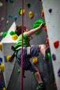 Young boy climbing up on practice wall in indoor rock gym Royalty Free Stock Photo