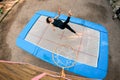View of young cheerful woman jumping on trampoline.