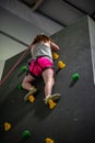 Young girl climbing up on practice wall in indoor rock gym Royalty Free Stock Photo