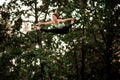 View on young woman jumping on large trampoline and doing twine in the air.