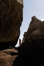 A woman standing on the rock and watching the ocean.