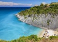 View on Zakynthos Island sand beach around rocks, swimming and toasting people on white sand beach, blue ultramarine water of Ioni