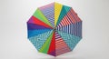 A top-down view of an open umbrella with a brightly colored geometric pattern of stripes, dots, and solid color panels Royalty Free Stock Photo