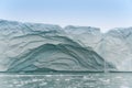 Viewed from sea a glacial wall has calved and collapsed,Ice fragments float in foreground.Melting ice has formed a waterfall Royalty Free Stock Photo