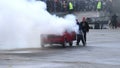 Viewers watching senior man extinguish stunt car fire, sequence