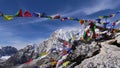Summit of mountain Kala Patthar with Buddhist prayer flags flying in the strong wind and snow-capped Himalayan mountains.