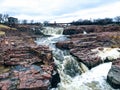 The Big Sioux River flows over rocks in Sioux Falls South Dakota with views of wildlife, ruins, park paths, train track bridge, tr Royalty Free Stock Photo