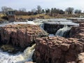 The Big Sioux River flows over rocks in Sioux Falls South Dakota with views of wildlife, ruins, park paths, train track bridge, tr Royalty Free Stock Photo