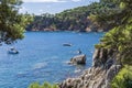 Views of the coast in `Punta des Forcats` with boats and people in the water in Calella de Palafrugell.