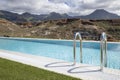 Views of a large luxurious swimming pool surrounded by the natural mountainous landscape