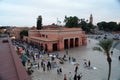 Views of the food market and shops of the Jemaa el Fna square in Marrakech with people at dusk