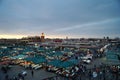 Views of the food market and shops of the Jemaa el Fna square in Marrakech with people at dusk