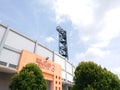 views of the orange football stadium entrance and towering floodlights and lush, fresh green trees