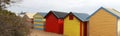 Views of rows of colourful beach bright painted summer holiday bathing box`s along a sandy beach on a sunny day, Brighton beach,