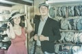 Vigorous young female and man choosing hats in the store