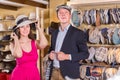 vigorous young female and man choosing hats in the store