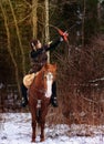 A Viking girl riding on horse painted in black runes. holds a bow and shoots it Royalty Free Stock Photo