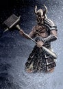 A Viking in a helmet with horns stands in the snow on the mountainside with a large hammer in his hands. A brutal warrior