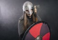 Viking stands with an ax on a gray background. A man in chain mail and a helmet holds a weapon. Medieval warrior in armor