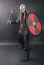 Viking stands with an ax on a gray background. A man in chain mail and a helmet waves his weapon. A medieval warrior in armor goes