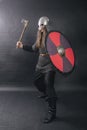 Viking stands with an ax on a gray background. A man in chain mail and a helmet waves his weapon. A medieval warrior in armor goes