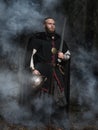 Viking with sword and helmet on a background of smoky forest