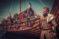 Viking warrior with axes standing near Drakkar on the seashore.